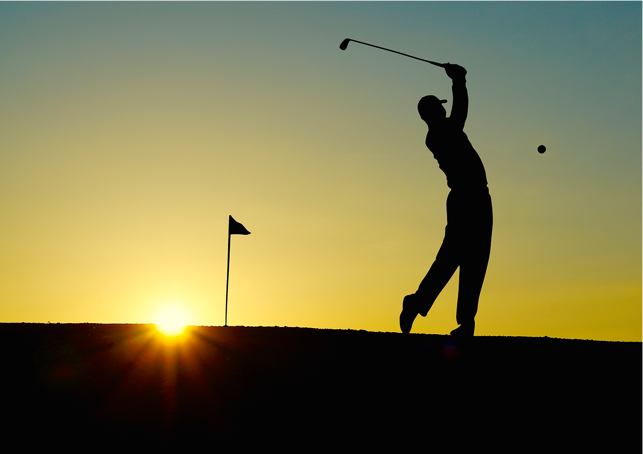 Image: Golfer swinging club at sunset